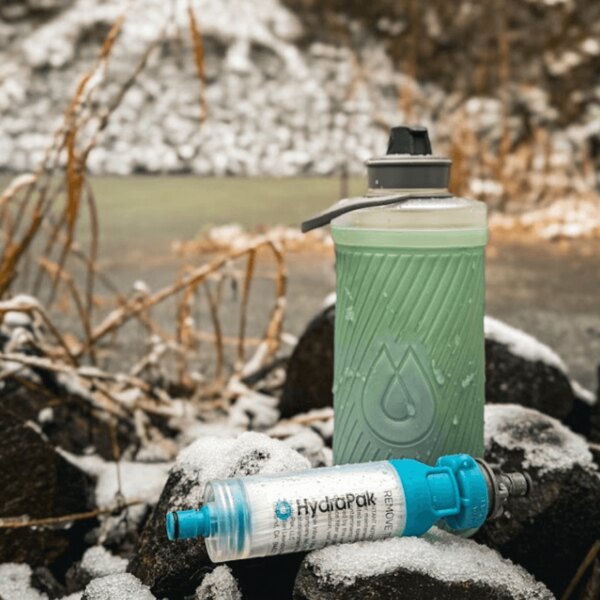 Hydrapak lahev a vodní filtr položené na sněhu. Outdoor hydratační systém v zimním prostředí. Foto: Rigad