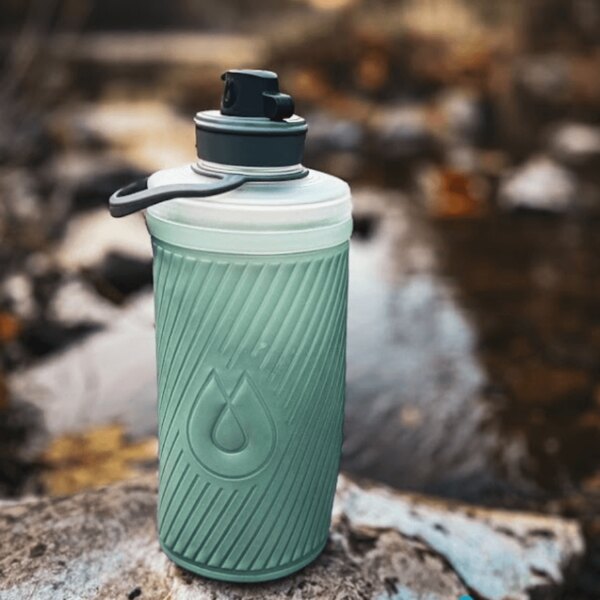 Hydrapak skládací lahev a vodní filtr používané u přírodního zdroje. Outdoor vybavení k hydrataci. Foto: Rigad