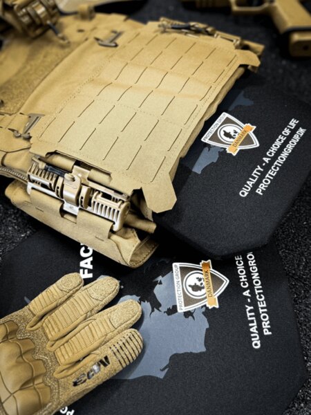 Plate carrier s vloženými balistickými pláty, laser-cut MOLLE a rychloodepínací přezky; v popředí taktické rukavice (PGD).