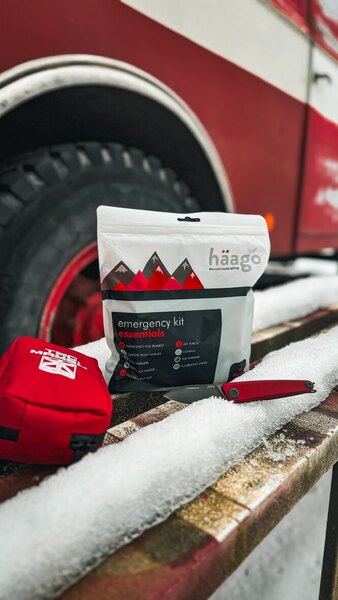 Nouzový zimní set Haago s termofólií a ohřívači rukou položený ve sněhu před vozidlem – praktická výbava do auta pro zimní sezónu 2025/26. Foto: Rigad