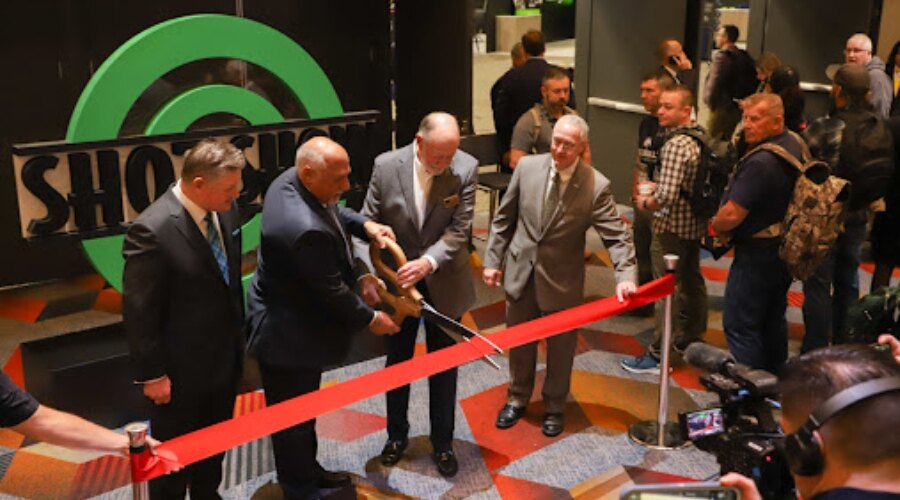 Muži přestřihávají červenou pásku na akci Shot show