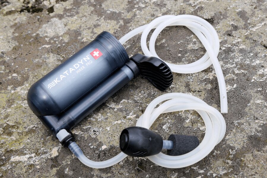 Pumpovací vodní filtr Katadyn Hiker Pro s hadičkami položený na kameni. Foto: Rigad