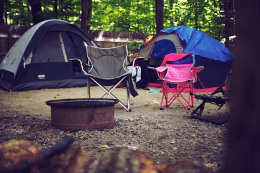 kempové židle před stanem v kempu. Zdroj: https://www.pexels.com/cs-cz/foto/drevo-krajina-dovolena-leto-2662816/