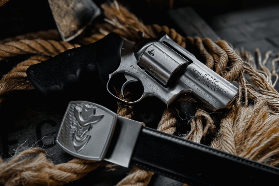 Revolver Ruger Super Redhawk Alaskan v ráži .454 Casull položený na laně vedle koženého opasku.