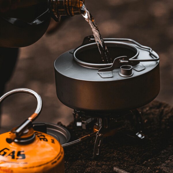 Outdoorové vaření v přírodě. Zdroj: https://www.pexels.com/cs-cz/foto/voda-misa-kempovani-lahev-20397578/