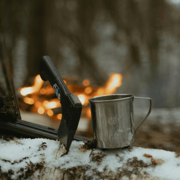 Bushcraftová sekera a plechový hrnek v lese u ohně. Zdroj: https://www.pexels.com/cs-cz/foto/ryma-studeny-snih-priroda-6204650/