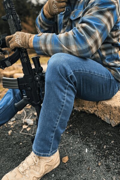 Muž v kalhotech Treadstone Jeans® Helikon-Tex® v kostkované košili s puškou. Foto: Rigad