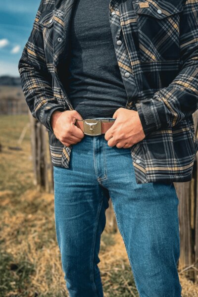 Muž v kalhotech Treadstone Jeans® Helikon-Tex® v kostkované košili se drží za opasek. Foto: Rigad