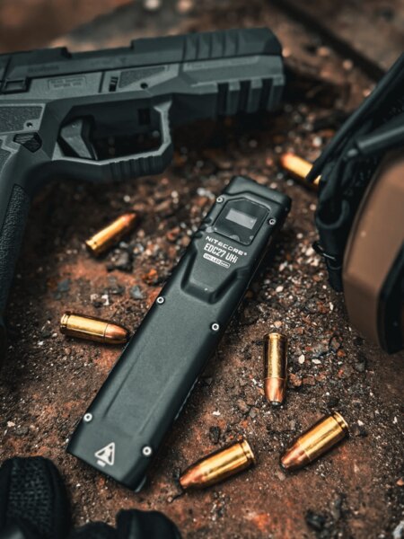Svítilna Nitecore EDC27 UHi s náboji a pistolí v pozadí. Foto: Rigad