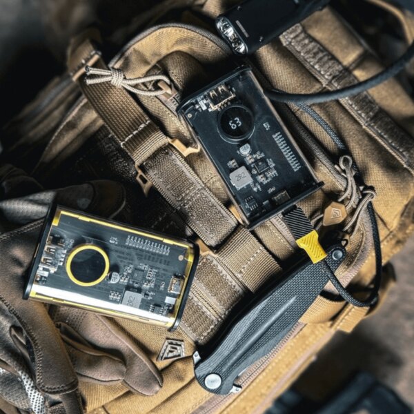 Powerbanka C4 Explosive Tactical®, 9600 mAh položená na taktické výstroji; transparentní tělo s displejem, rychlé nabíjení a robustní design do terénu. Foto: Rigad
