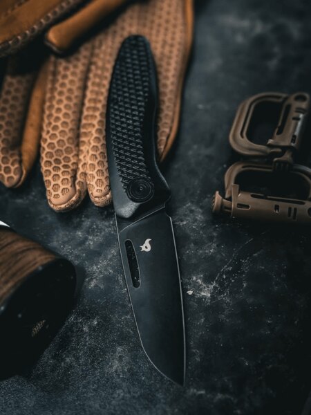 Moderní zavírací nůž Black Fox® s černou čepelí položený na pracovní rukavice. Foto: Rigad