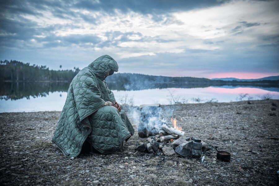 Nouzové zateplení v zimě – použití zatepleného ponča při nocování venku v chladných podmínkách. Foto: Helikon-Tex, Rigad