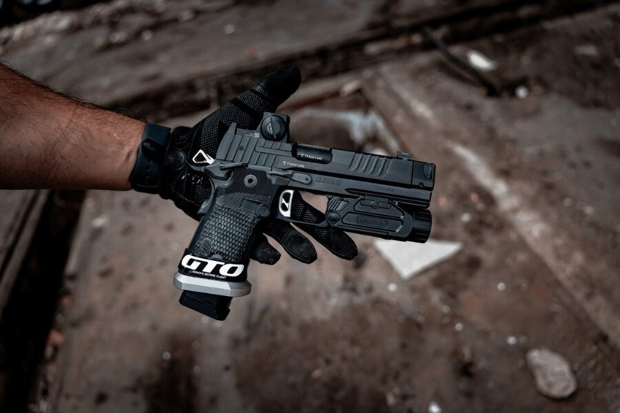 Full-size pistole s kolimátorem a podvěsnou svítilnou při držení obouručním úchopem – Foto: Rigad