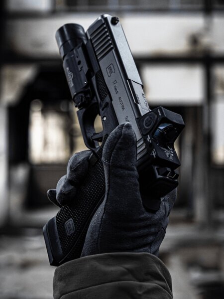 Pistole Glock 17 Gen6 s kolimátorem Trijicon RMR a zbraňovou svítilnou v ruce střelce. Foto: Rigad