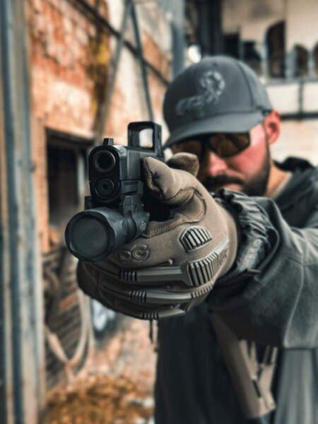 Střelec míří s pistolí Glock s kolimátorem Aimpoint COA, pohled přes zbraň v praxi, Foto: Rigad