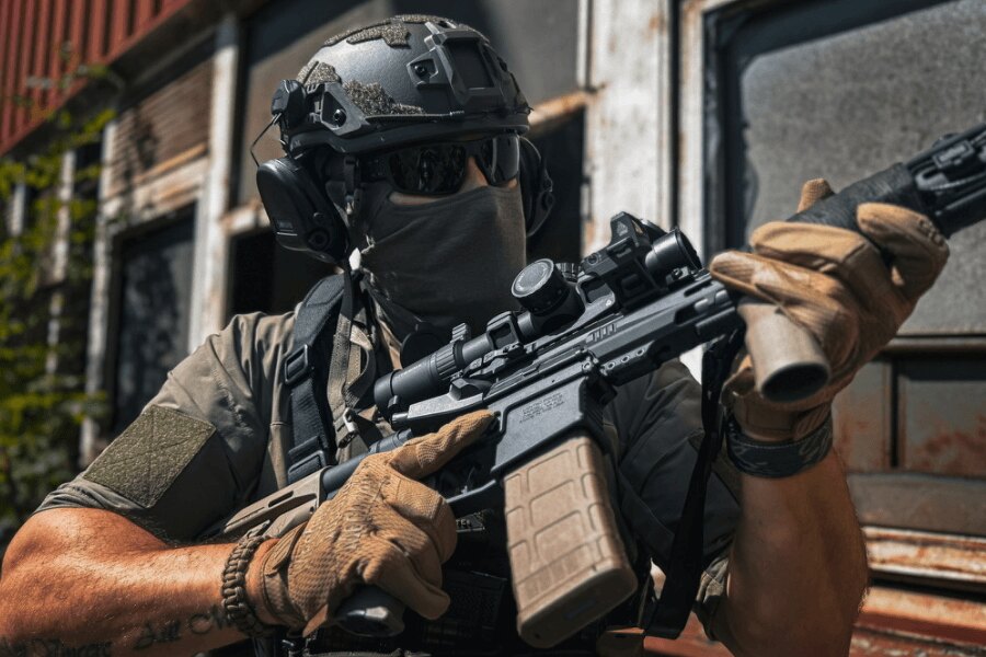 Střelec s puškou AR-15 osazenou optikou při míření v terénu, Foto: Rigad