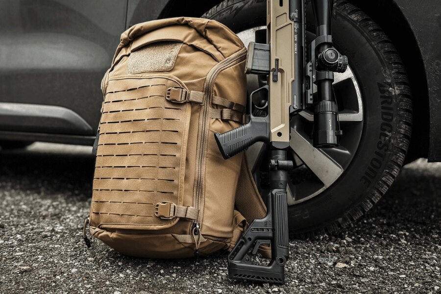 Batoh Vertx Siege Tactical Sling opřený o auto s puškou. Foto: Rigad