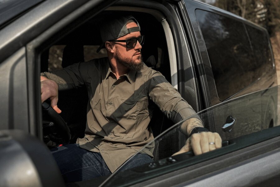 Muž v košili Vertx sedí v autě a sleduje okolí. Foto: Rigad