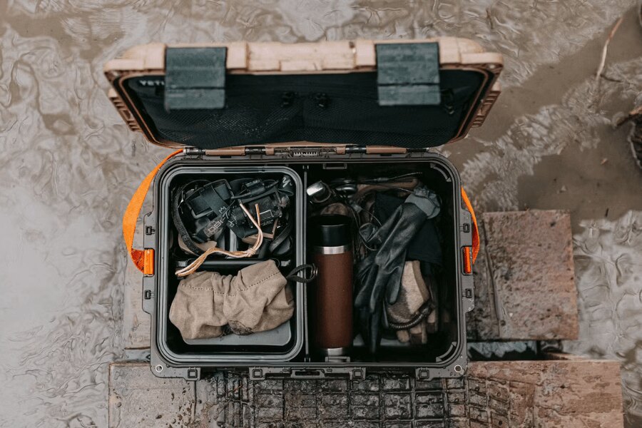 Odolný gear box YETI LoadOut GoBox s vybavením položený v mokrém terénu