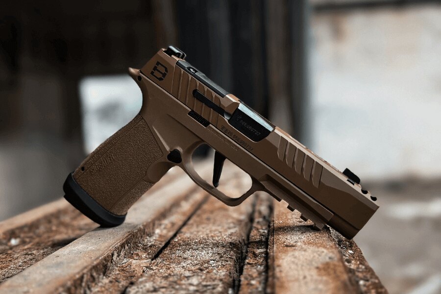 Moderní samonabíjecí pistole v ráži 9 mm Luger položená na dřevěném podkladu.