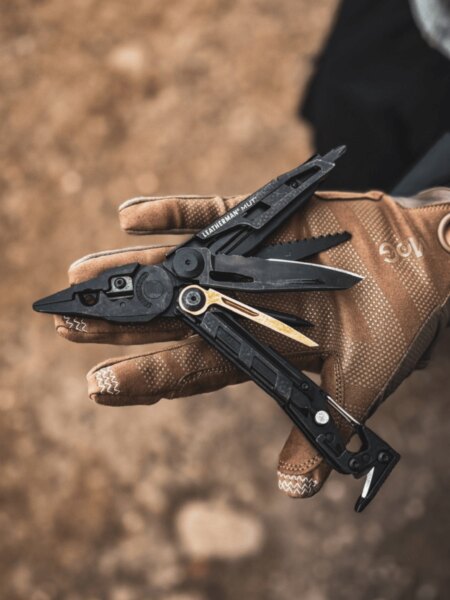 Multitool Leatherman MUT rozložený na dlani v taktické rukavici.