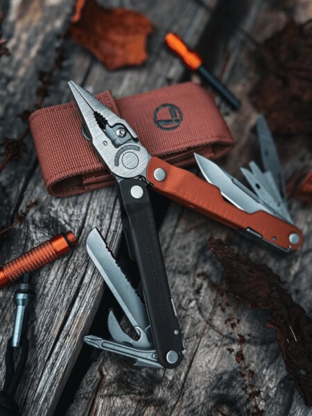 Multifunkční nástroj Leatherman Rebar s rozloženými kleštěmi a vysunutými nástroji na dřevěném povrchu.