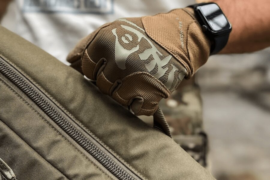 Detail taktické rukavice Helikon-Tex Range při manipulaci se střeleckou taškou.