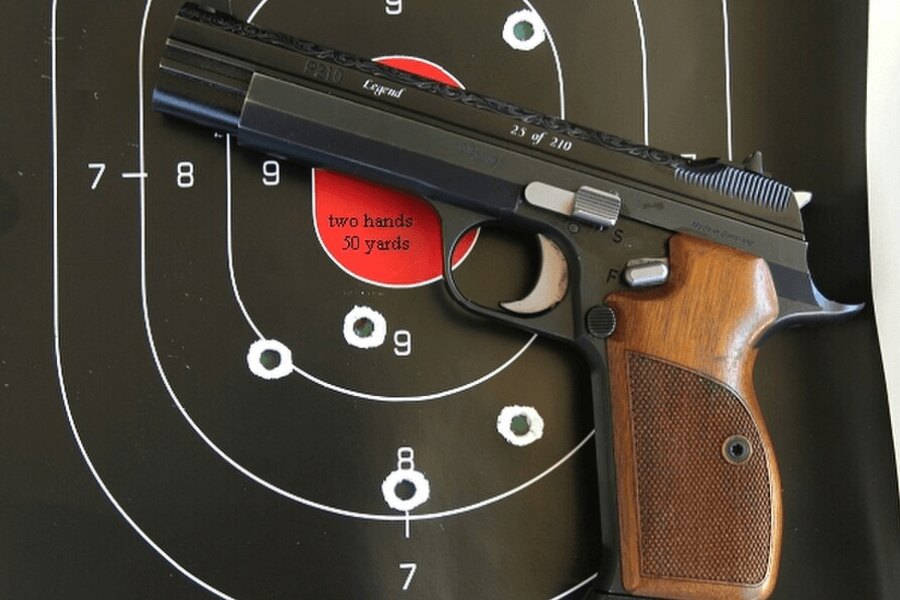 Pistole SIG P210 položená před střeleckým terčem.