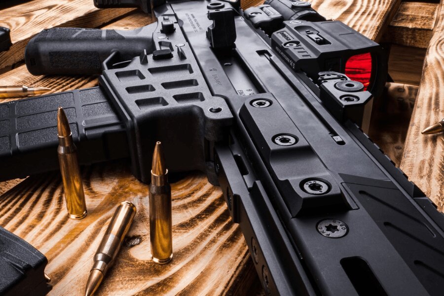 Detail samonabíjecí pušky CZ BREN 2 s kolimátorem na dřevěném stole.