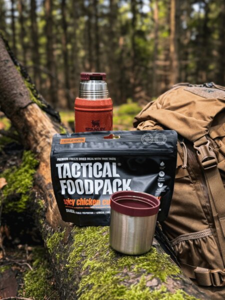 Lyofilizované jídlo Tactical Foodpack s termoskou Stanley, hrnkem a batohem v lese.