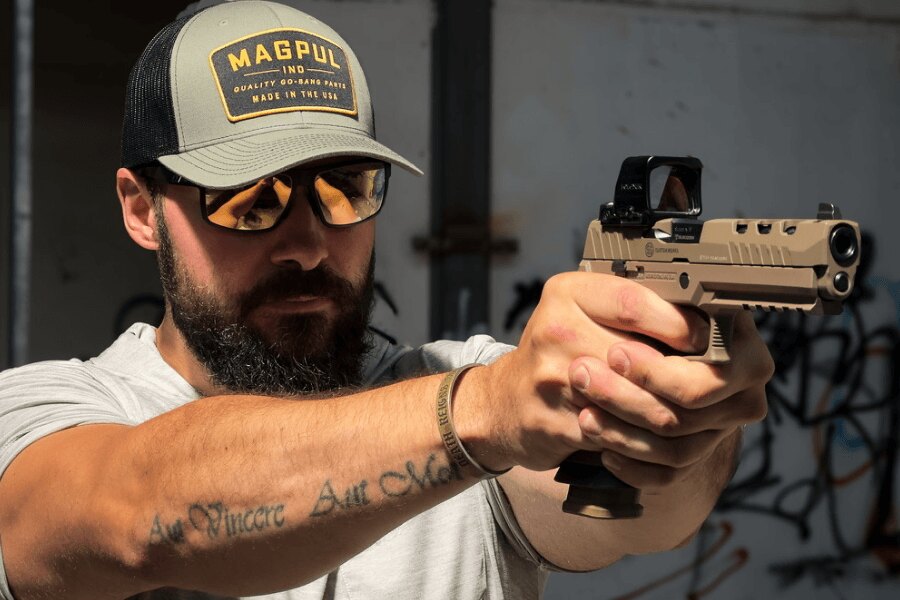 Střelec v ochranných brýlích míří pistolí SIG Sauer P320 DH3 s kolimátorem Holosun.