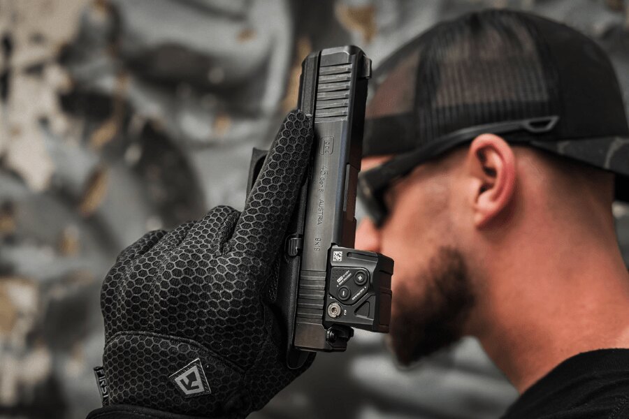 Detail pistole Glock 45 s kolimátorem držené v rukavici.