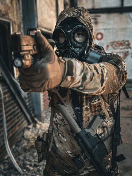 Střelec v celoobličejové ochranné masce s filtrem při míření pistolí.