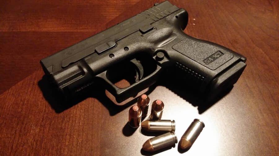 Pistol s náboji položená na stole
