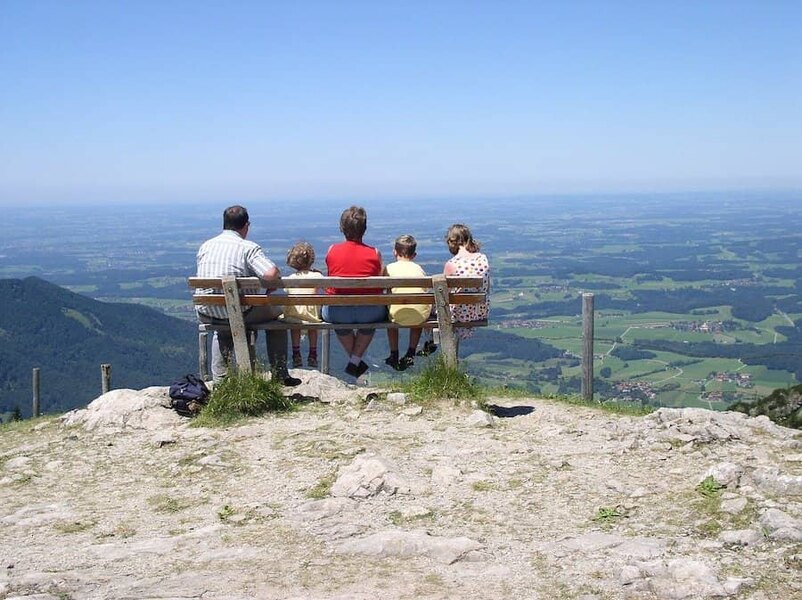 Rodina sedící na lavičce na vrcholu kopce 