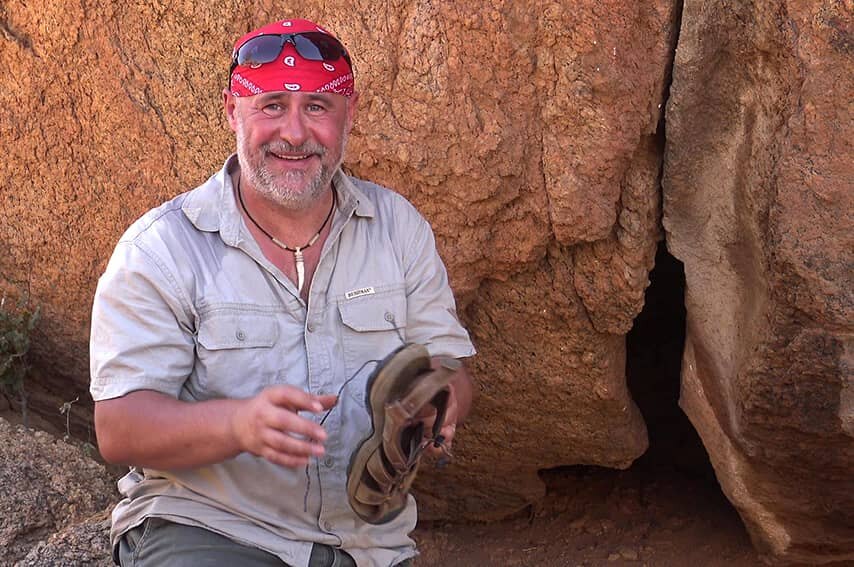 Muž stojící u skály v Kalahari