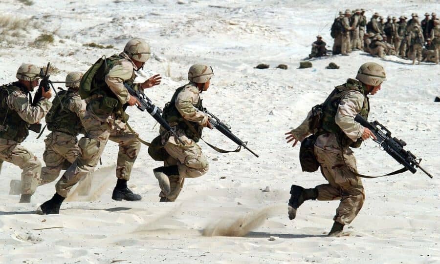 Američtí vojáci běžící pouští v armádním vybavení