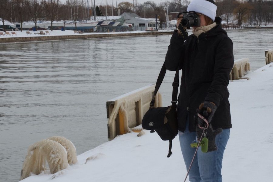 Žena stojící u vody s vodítkem a s fotoaparátem